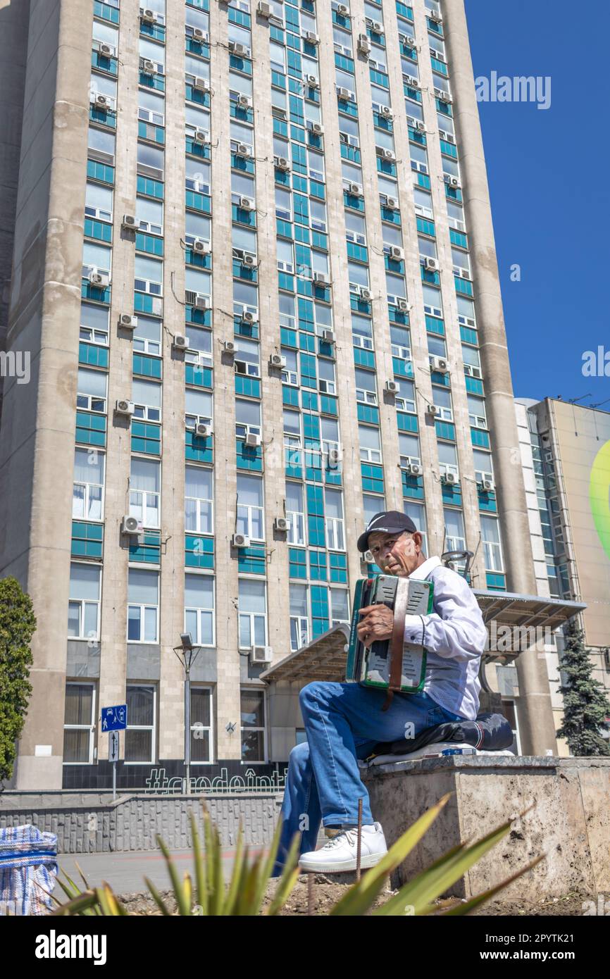 CHISINAU, MOLDOVA-MAY 12, 2022: Old Man Musician Busking Playing accordion Outdoors In Central Street Stock Photo