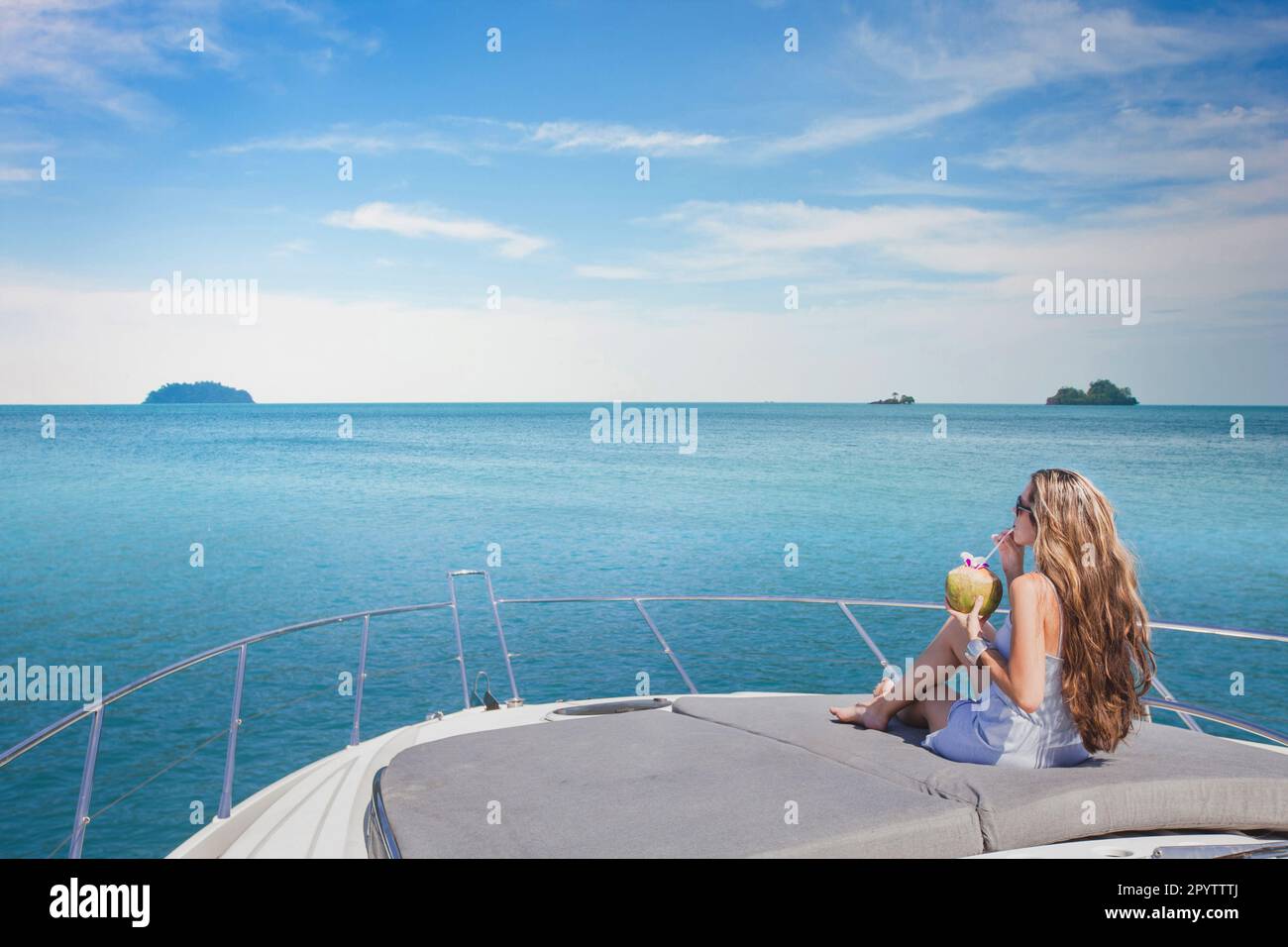 luxury travel, woman relaxing on luxurious boat and drinking coconut