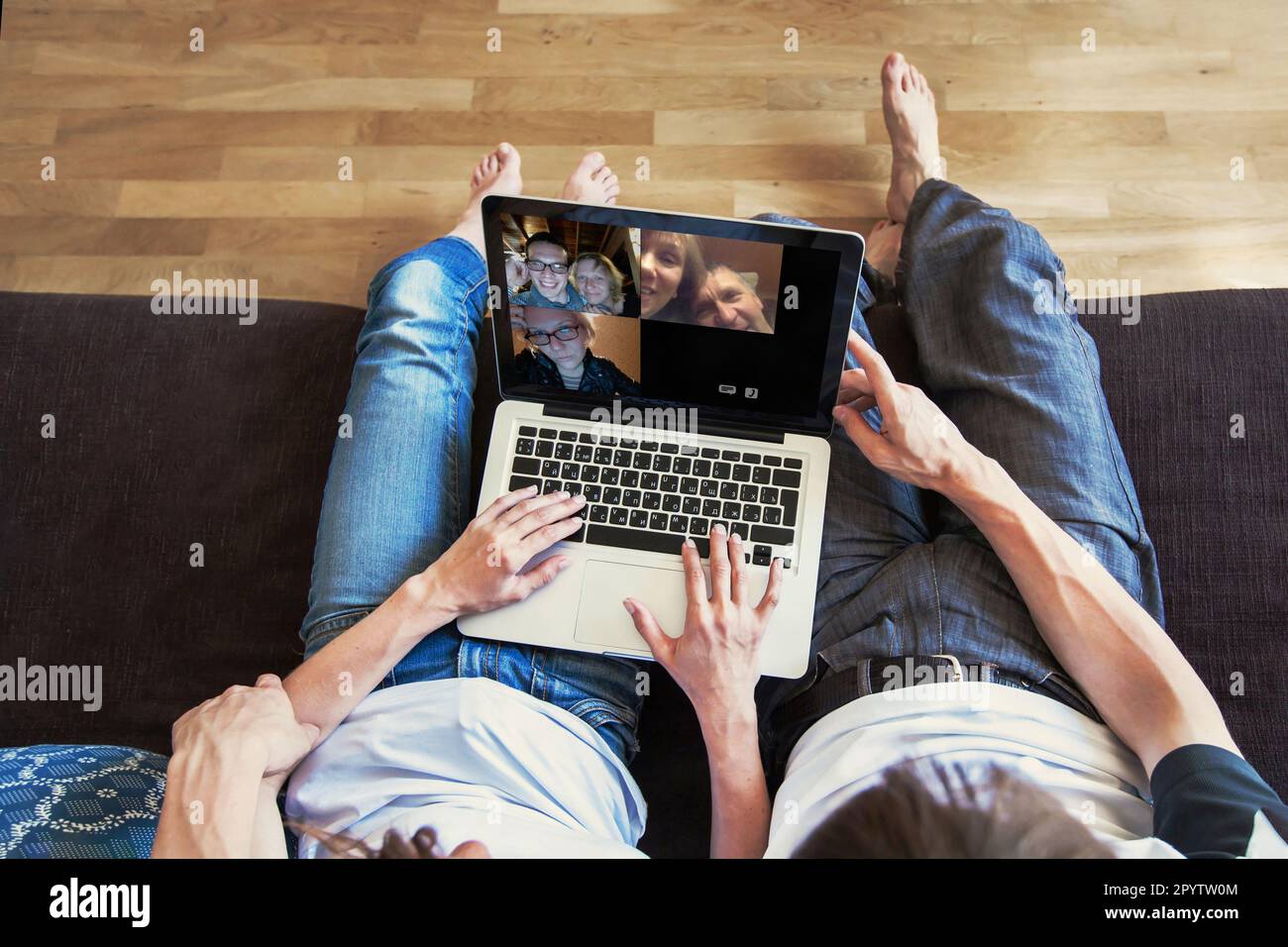 group video call with family and friends, couple sitting on the couch using laptop computer Stock Photo