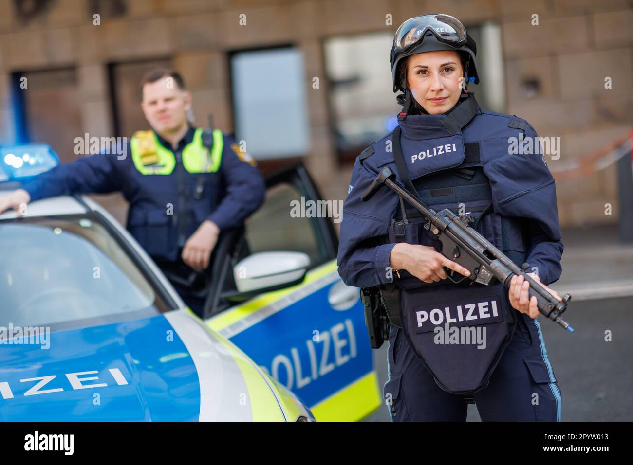05 May 2023, Bavaria, Nuremberg: Police Master Marie-Sophie Andersch wearing a ballistic protective helmet and a bulletproof vest of protection class four and Police Superintendent Sebastian Walter with body cam and bulletproof vest of protection class one stand by a patrol car at the Central Franconia Police Headquarters on the sidelines of a press conference on the Bavaria-wide situation report on violence against police officers 2022. Police officers are supposed to provide protection through their work - and regularly become targets of violence in the process. According to the Ministry of Stock Photo