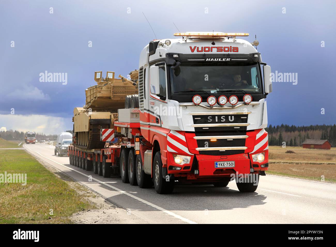 Sisu Polar Hauler Vuorsola pulls oversize load of American M1 Abrams military tank in traffic. Convoy of 3 transports. Aura, Finland. April 28, 2023. Stock Photo