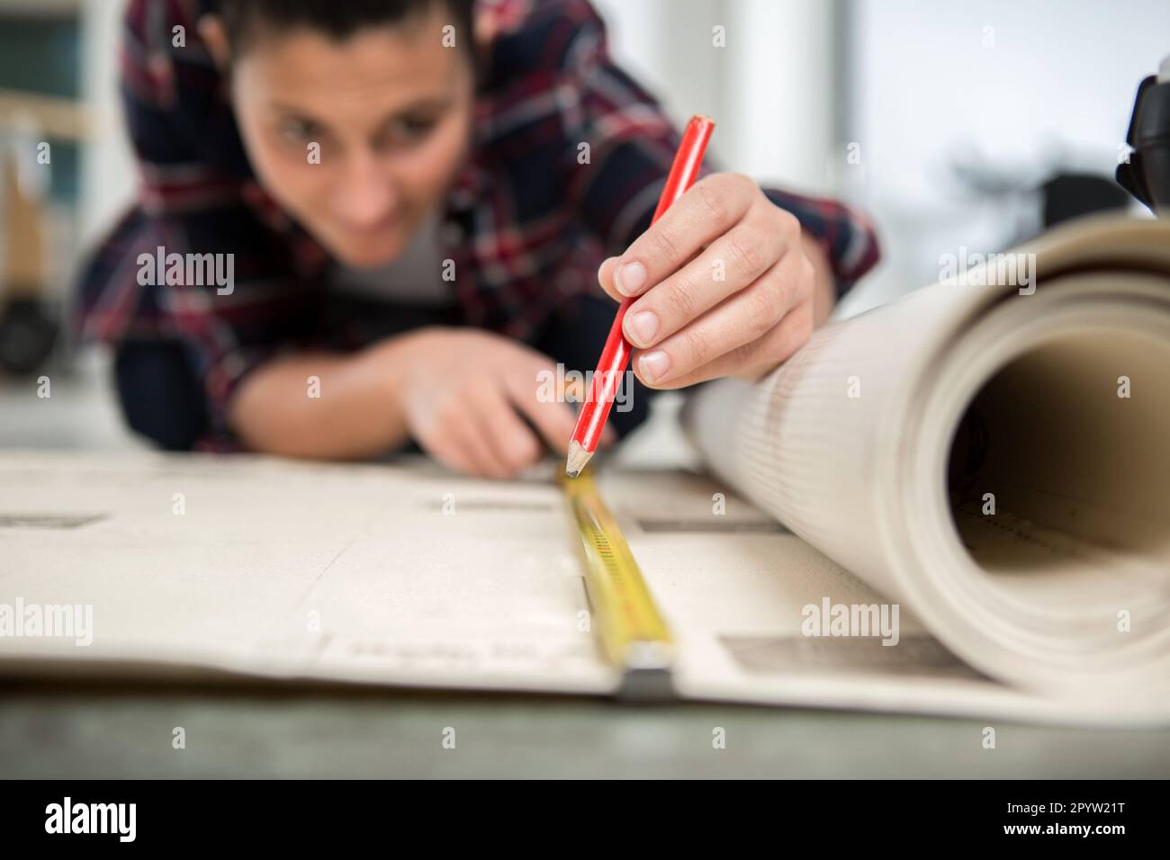 female repairman measuring carpet on floor Stock Photo