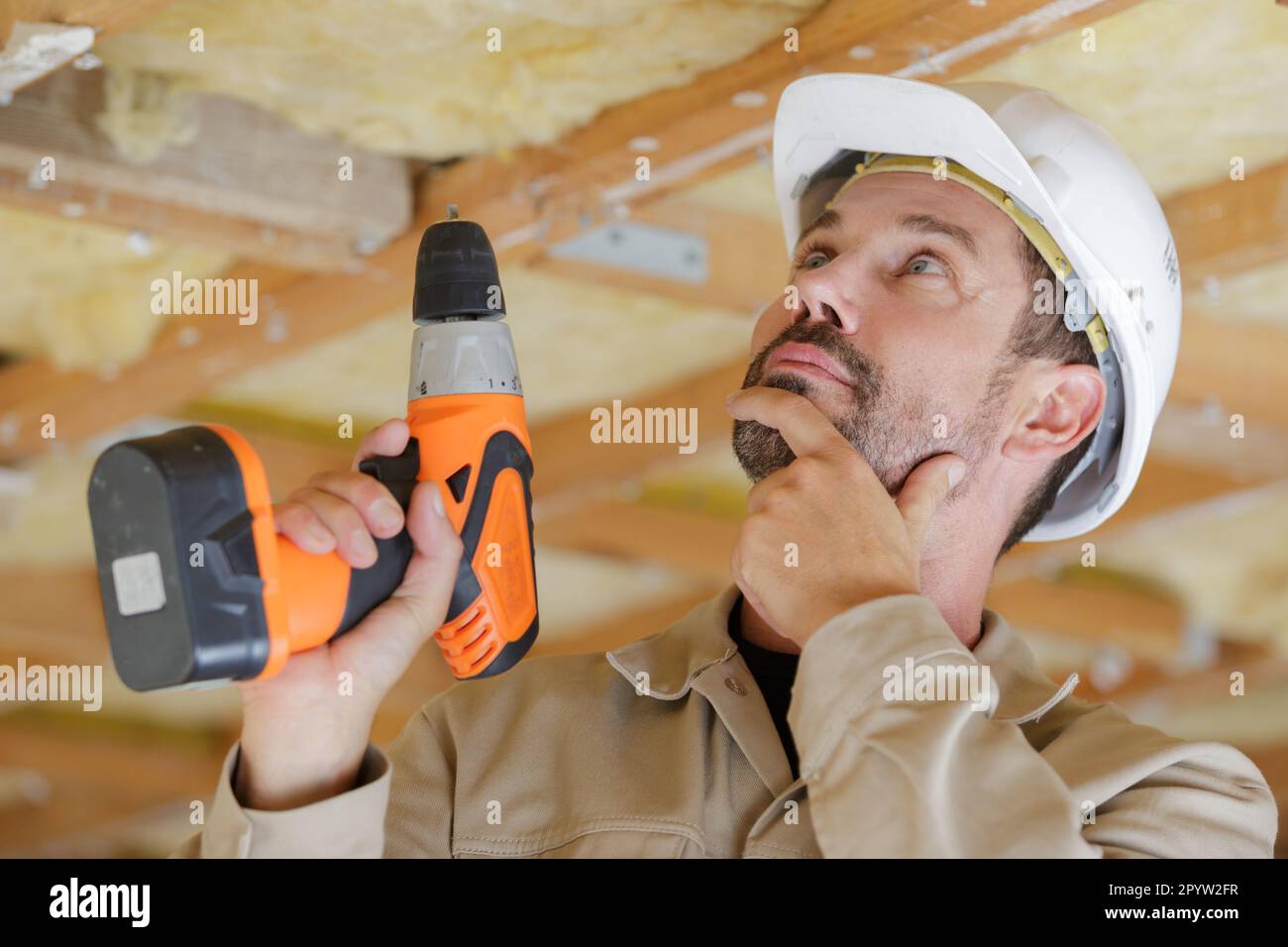 portrait of a worker drilling the ceiling Stock Photo