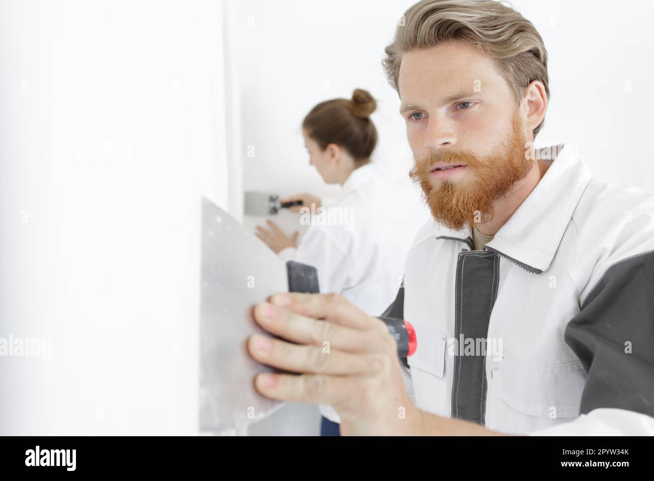 worker plastering a wall using a putty knife Stock Photo