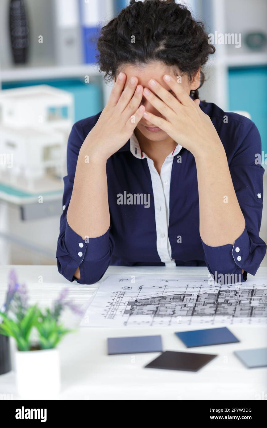 worried architect analyzing blueprints Stock Photo