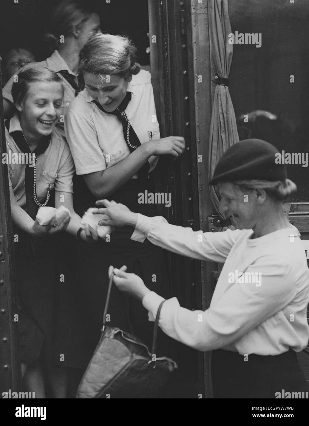 Young girls at the departure to the summer holiday camp at the Baltic Sea. A mother distributes provisions. [automated translation] Stock Photo