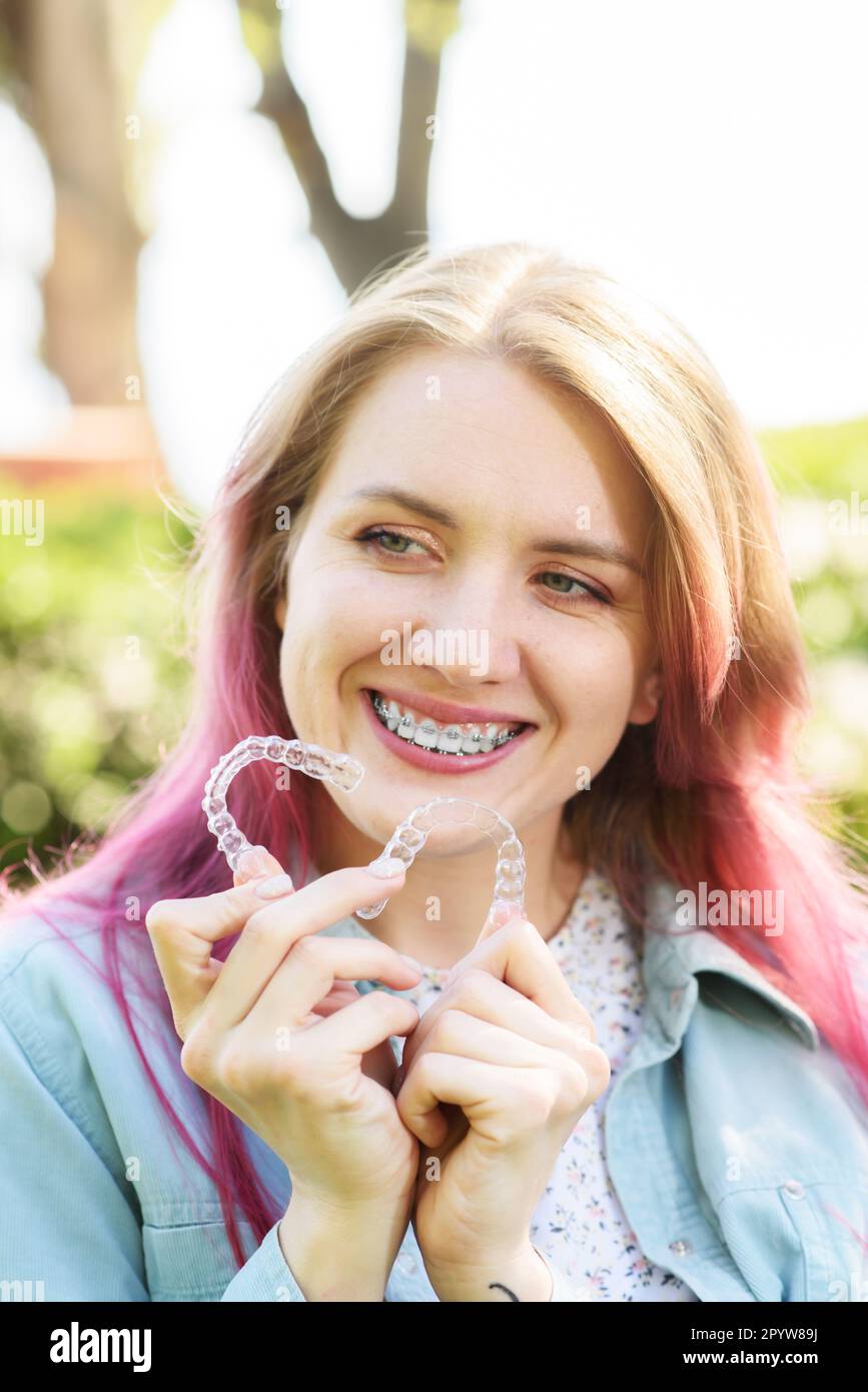 Dental care.Smiling happy girl with braces on her teeth holds aligners