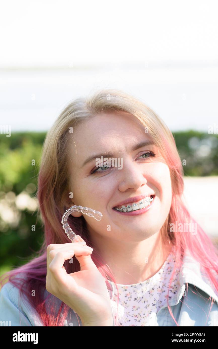 Dental care.Smiling happy girl with braces on her teeth holds aligners