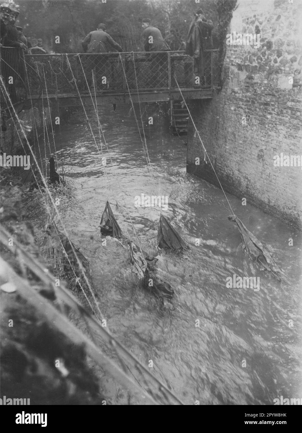 Soldiers have their soiled uniforms rinsed in a river of washer