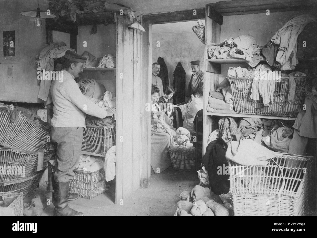 A soldier sorts dirty laundry in the laundry of an army corps on the Eastern Front. In the background, women are busy mending damaged pieces. [automated translation] Stock Photo