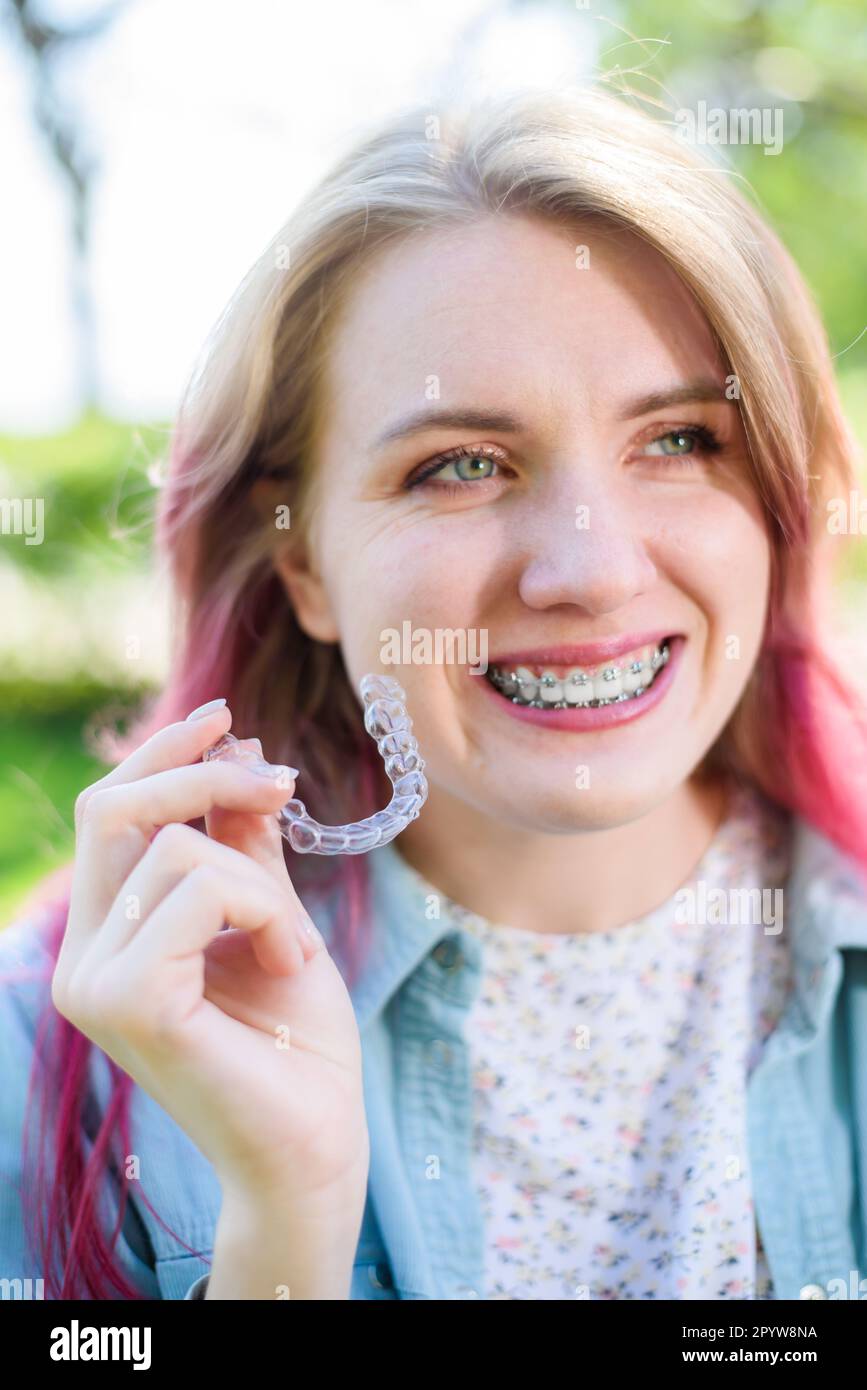 Dental care.Smiling happy girl with braces on her teeth holds aligners