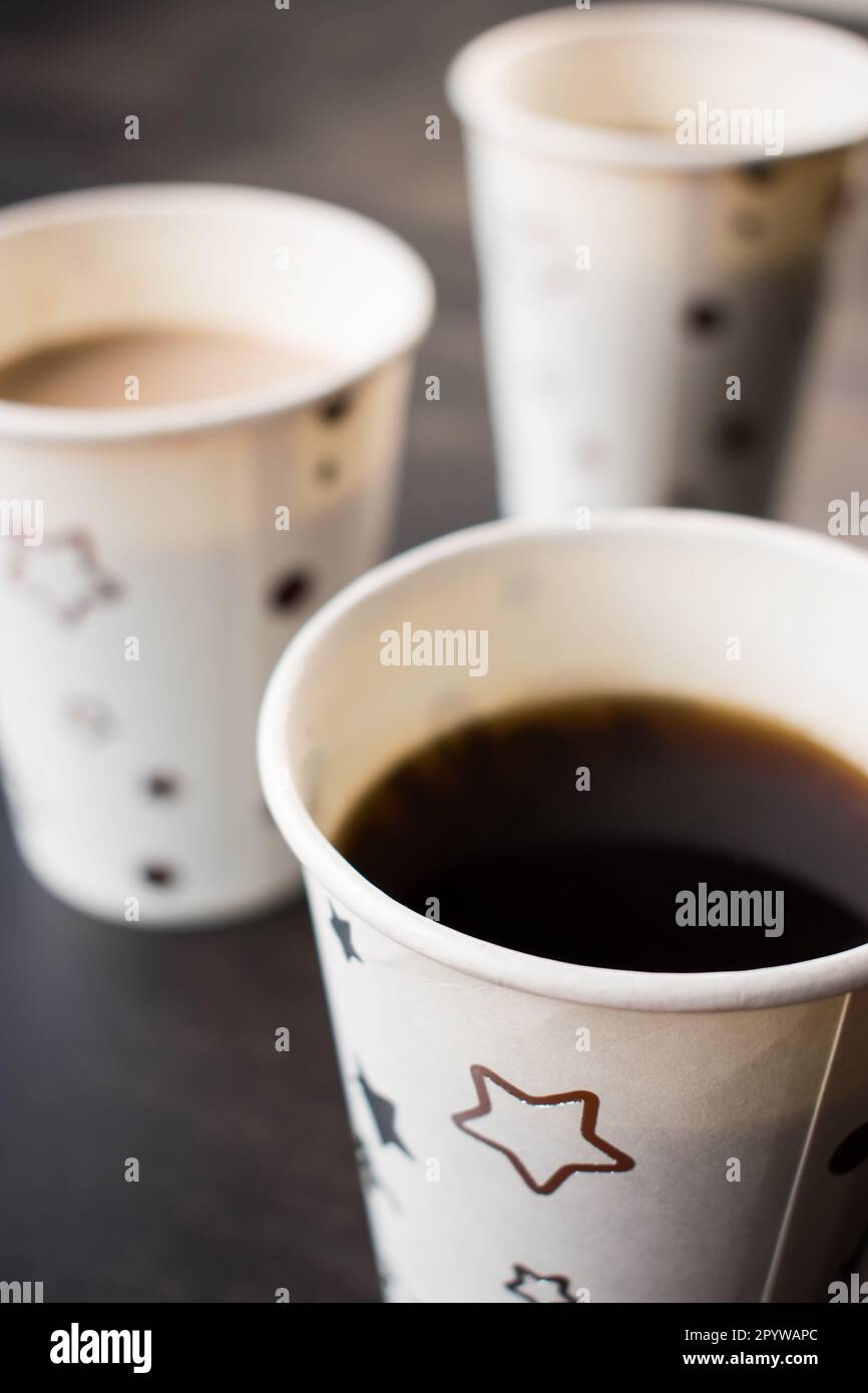 A close-up shot of two ceramic coffee cups sitting on a black table with a star pattern Stock Photo