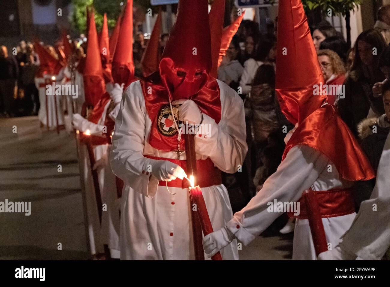 Cofradias wearing red cone shaped hoods light their candles during the midnight silent
