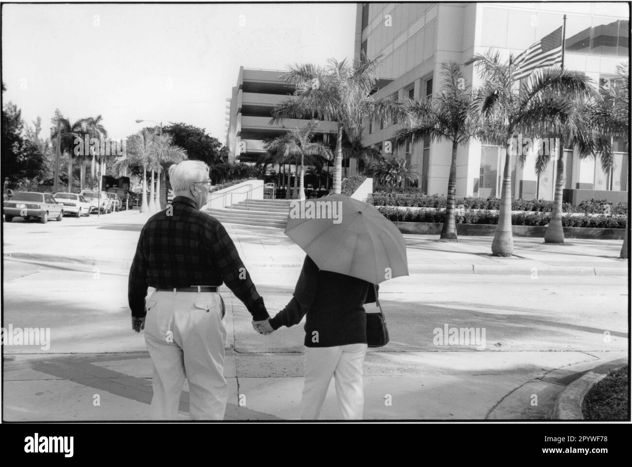 Love and marriage: married couples. Elderly couple in Miami (Florida, USA) with an umbrella as sun protection. Street scene, black and white. Photo, 1995. Stock Photo