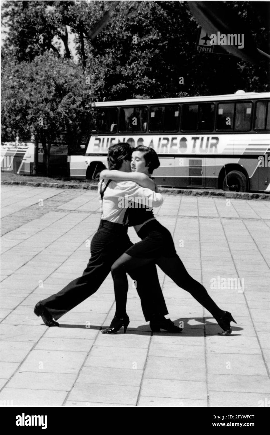Buenos Aires, Argentina. Music, ballroom dancing, street dance: Tango. Dancing couple dances tango on the street as a show for tourists. Street scene, black and white. Photo, 1997. Stock Photo