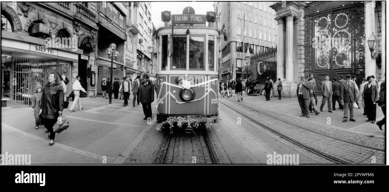 Istanbul (Turkey), Tram in the pedestrian and shopping street Istiklal Caddesi (Independence Street) in the Beyoglu district. Tram line 1 from Tünel Square via Galatasaray Square to Taksim Square. 180° panorama, black-and-white. Photo, 1996. Stock Photo