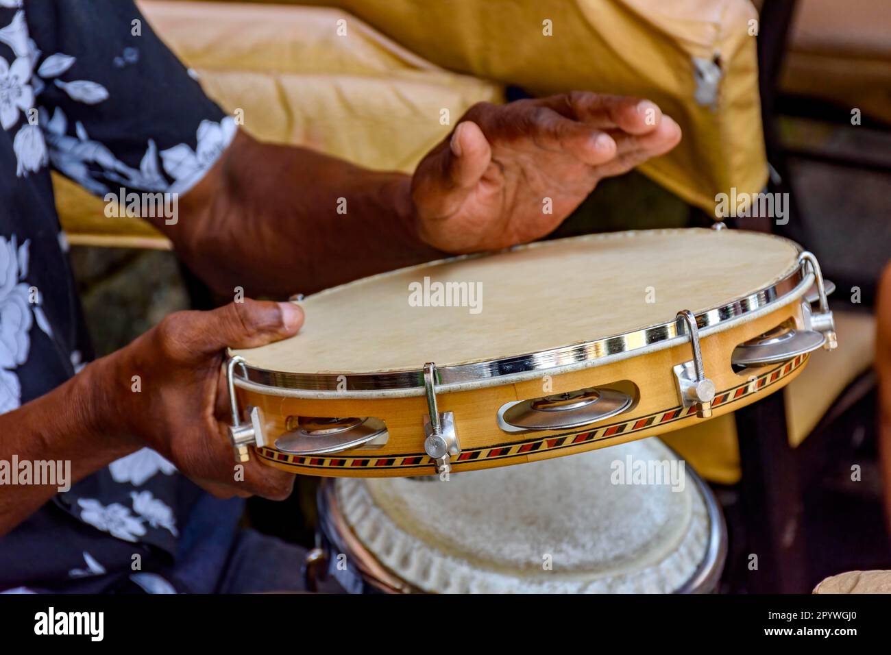 Hands and instrument of musician playing tambourine in the streets of