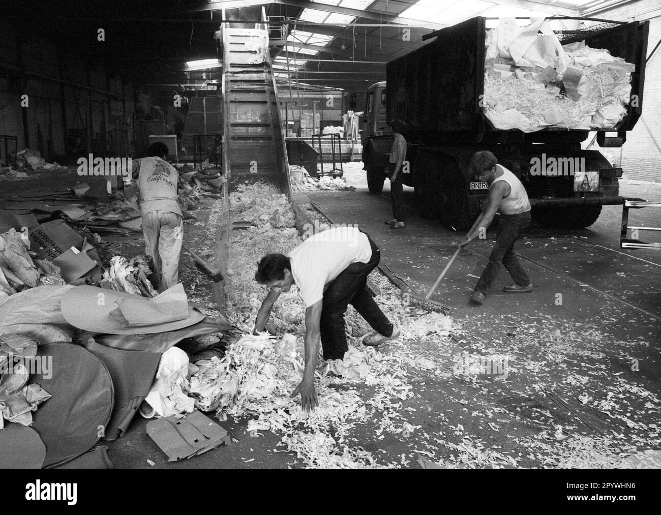 DEU , GERMANY Waste paper is being processed by workers in a