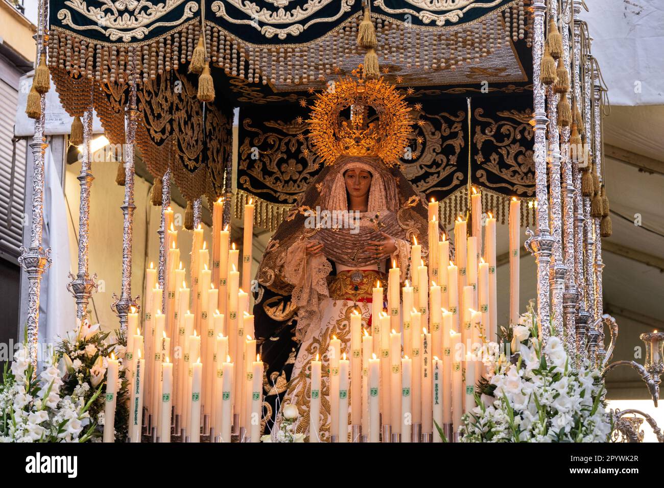 A massive platform with a statue of the Virgin Mary surrounded by candles in a procession during Holy Week or Semana Santa, April 5, 2023 in Ronda, Spain. Ronda, first settled in the 6th century B.C. has been holding Holy Week processions for over 500-years. Stock Photo