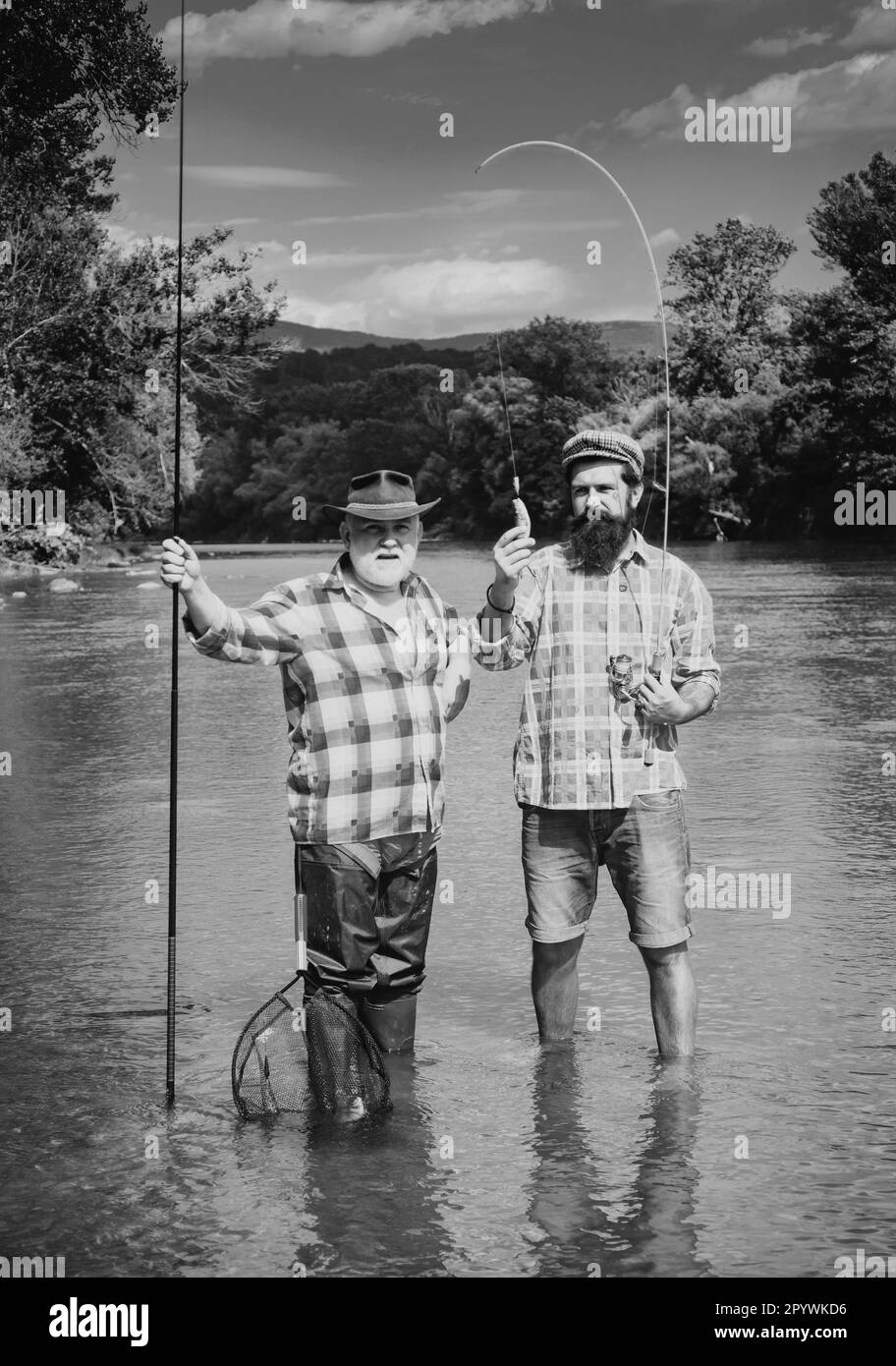 Fisherman and trophy trout. Young man and old mature man fly fishing. Difference between fly fishing and regular fishing. Anglers. Stock Photo