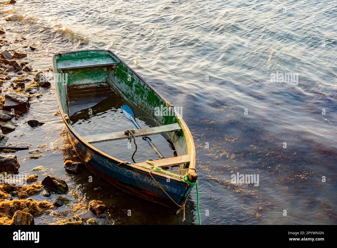 Old wooden fishing boat floating over seawater at sunset, Buzios, Rio de Janeiro, Brasil Stock Photo