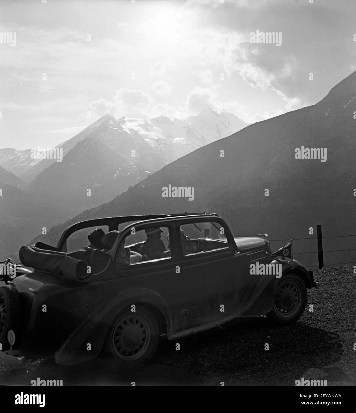 A car stands on a viewing platform. In the background, the panorama of the Grossglockner. Stock Photo