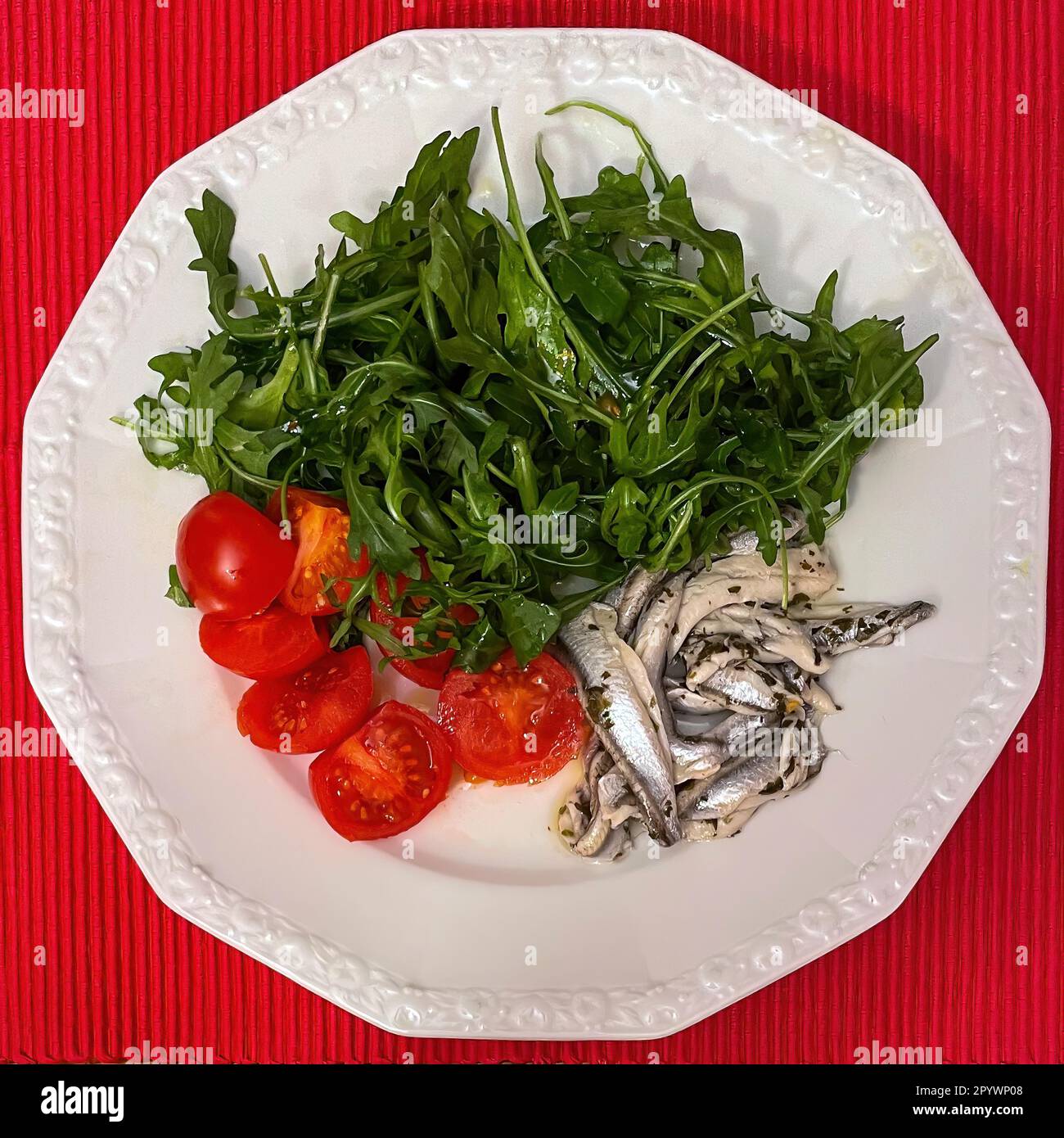 Italian dish from Italian cuisine served on a plate Starter Primo Piatto Marinated anchovies Alici marinate with fresh ruccola Ruccola salad and Stock Photo