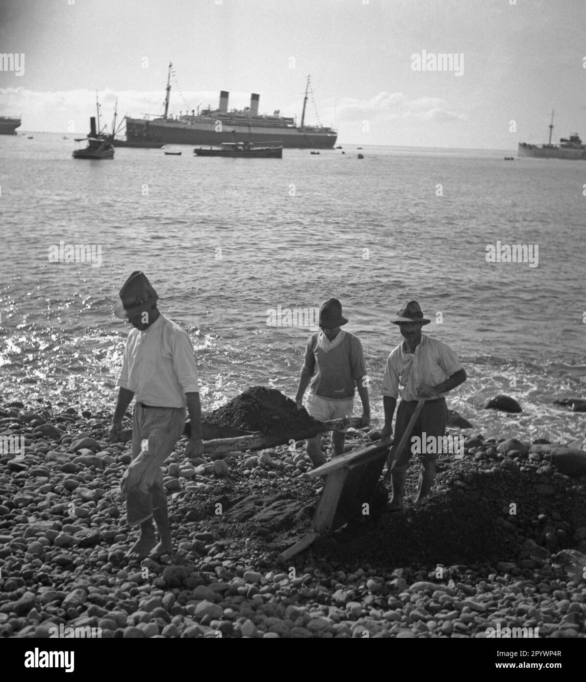 workers-carry-earth-away-from-the-beach-in-the-background-is-the-ship