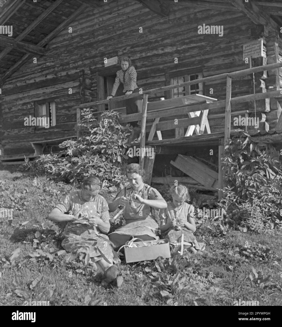 Women and girls do their handicrafts in the garden. Undated photo from