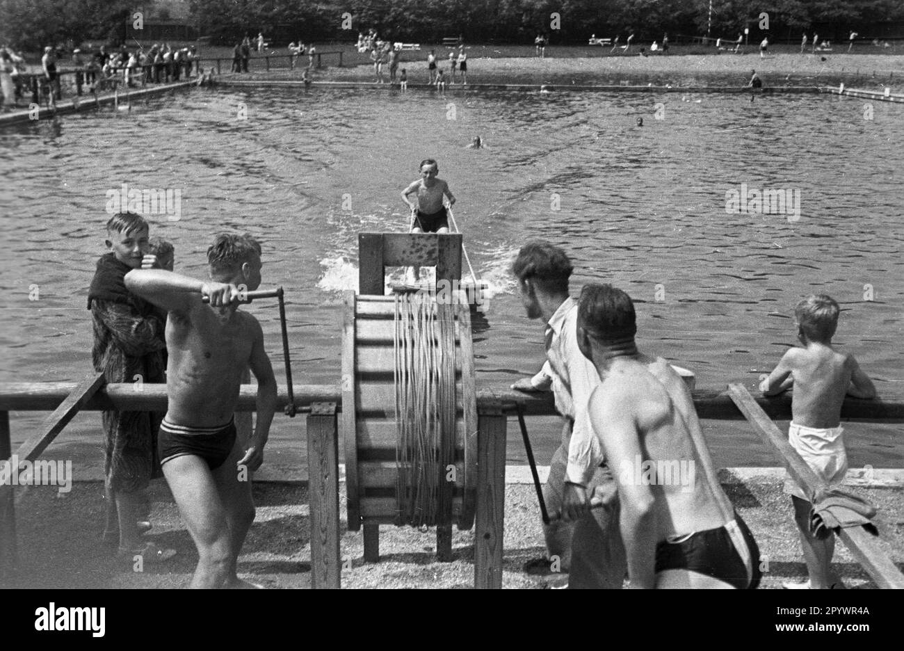 Muscle powered water ski facility in Altteich (Stary Staw, today Ostrow Wielkopolski). A boy with skis is pulled across a water basin with a crank. Stock Photo