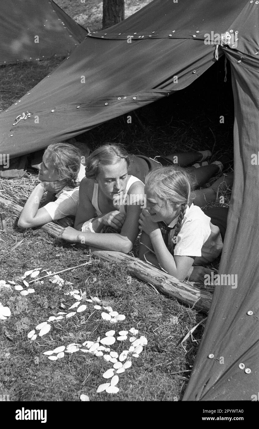 Girl in a tent at the summer camp of the Bund Deutscher Maedl (League of German Girls) in Karlshagen. They formed the word ETA from shells. Undated photo from around 1937. Stock Photo