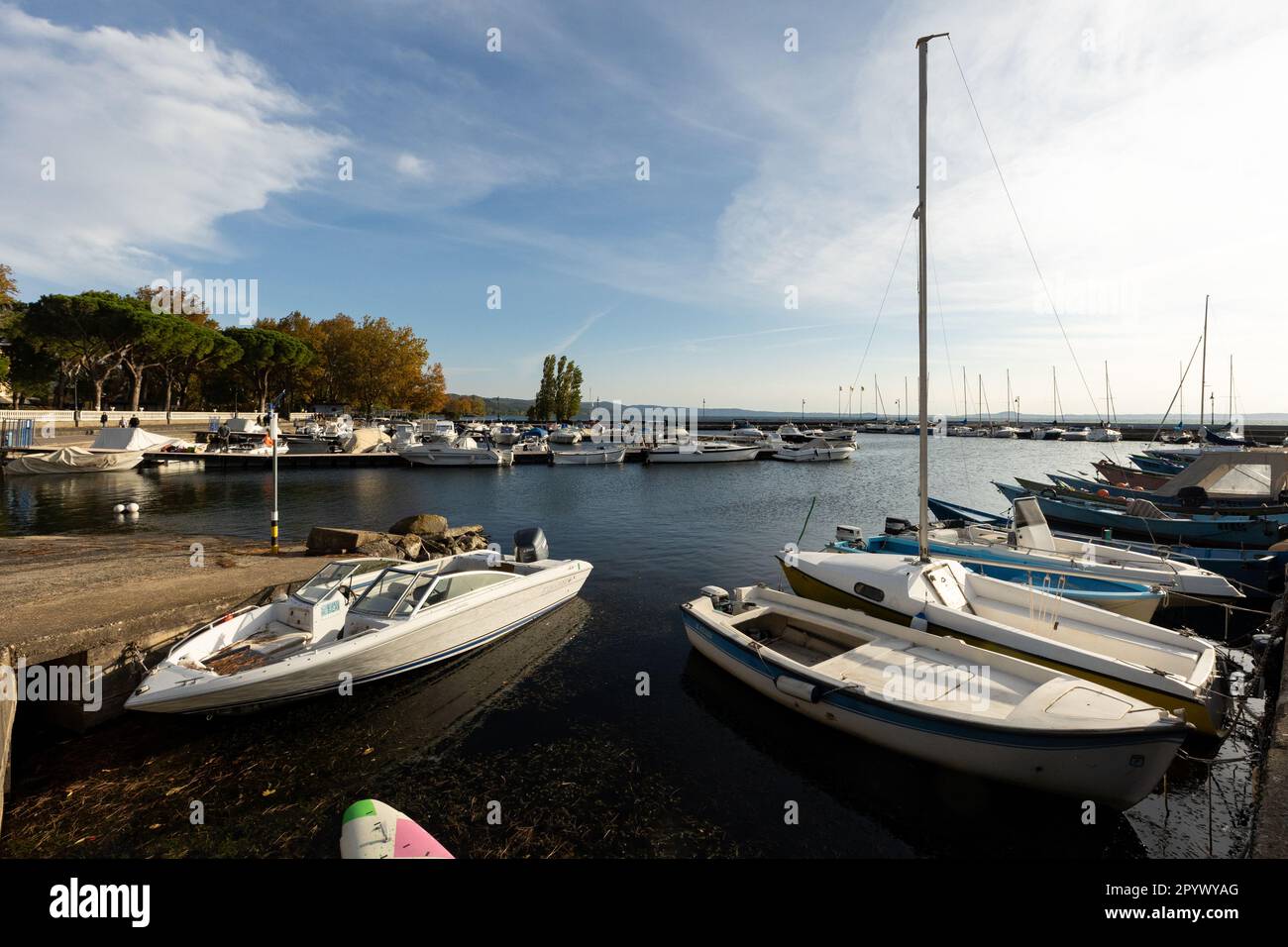 Picturesque Bolsena Lake at Dusk: peaceful evening at Bolsena with boats gently bobbing on the calm water as the sunset paints the sky with warm color Stock Photo