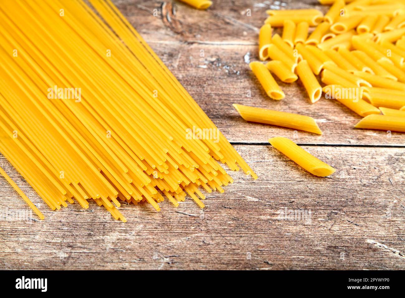 Dry uncooked pasta on a wood  kitchen table Stock Photo