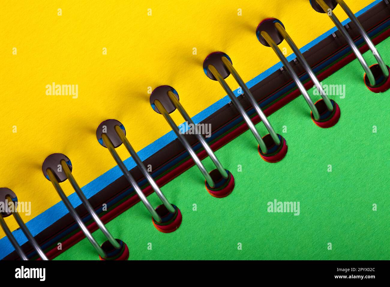 Spiral binder notebook open with green and yellow pages on display