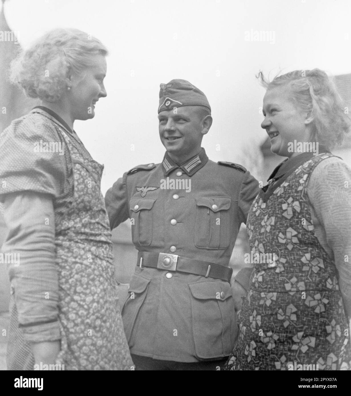 A soldier with two young women probably on a farm near Neustrelitz. Undated photo. Stock Photo