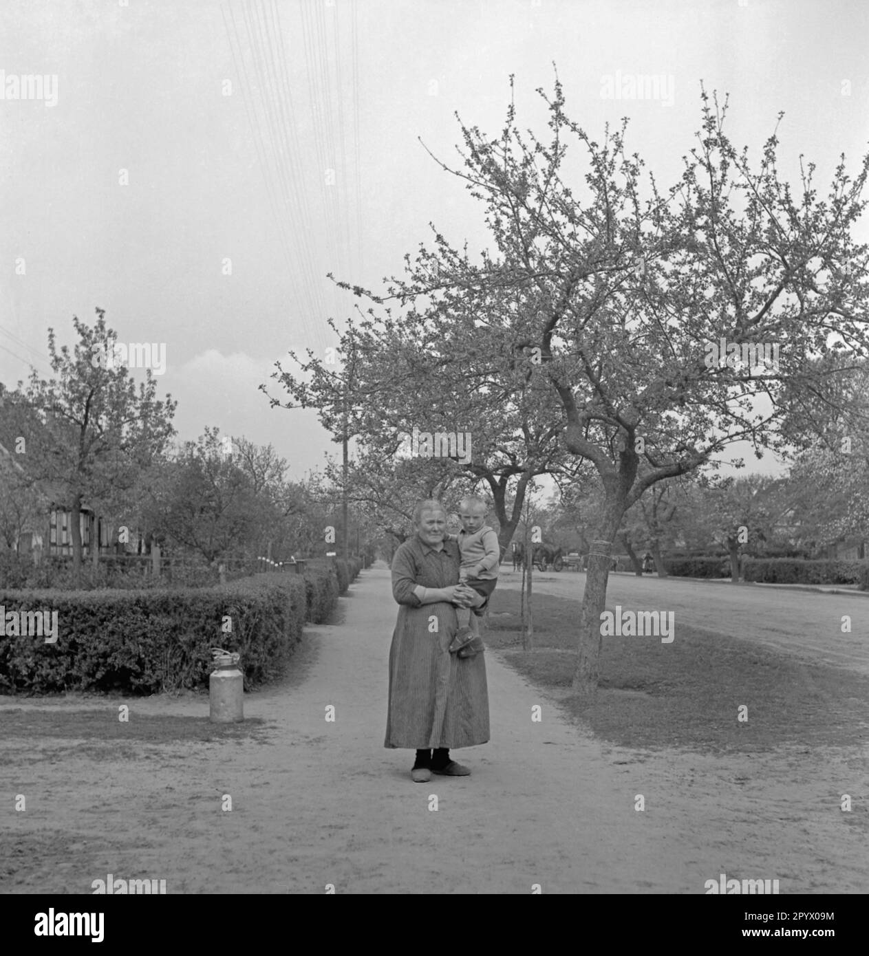 a-farmer-with-a-little-boy-in-her-arms-at-a-settlement-near-neustrelitz