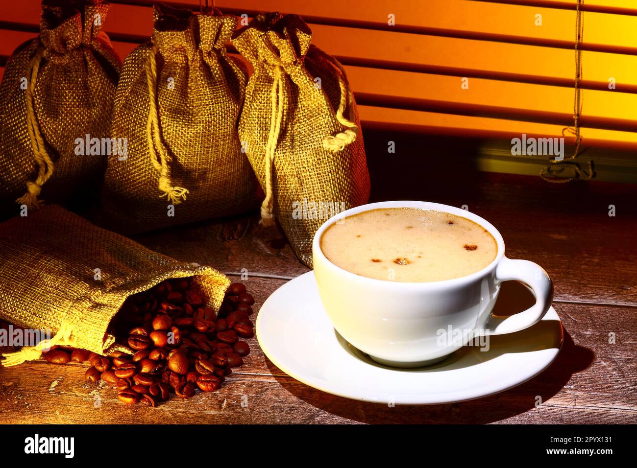 Coffee cup filled with coffee set against a kitchen window blind with