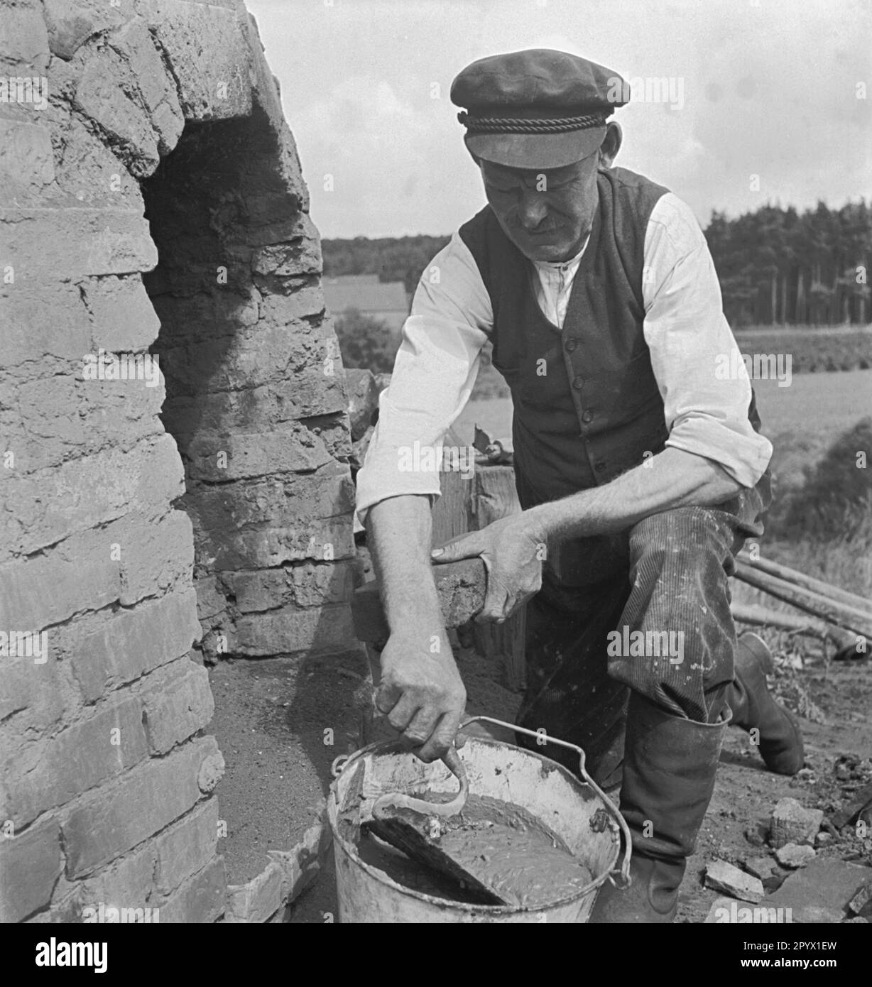 Man repairing a tar kiln for pyrolytic in Mecklenburg. In