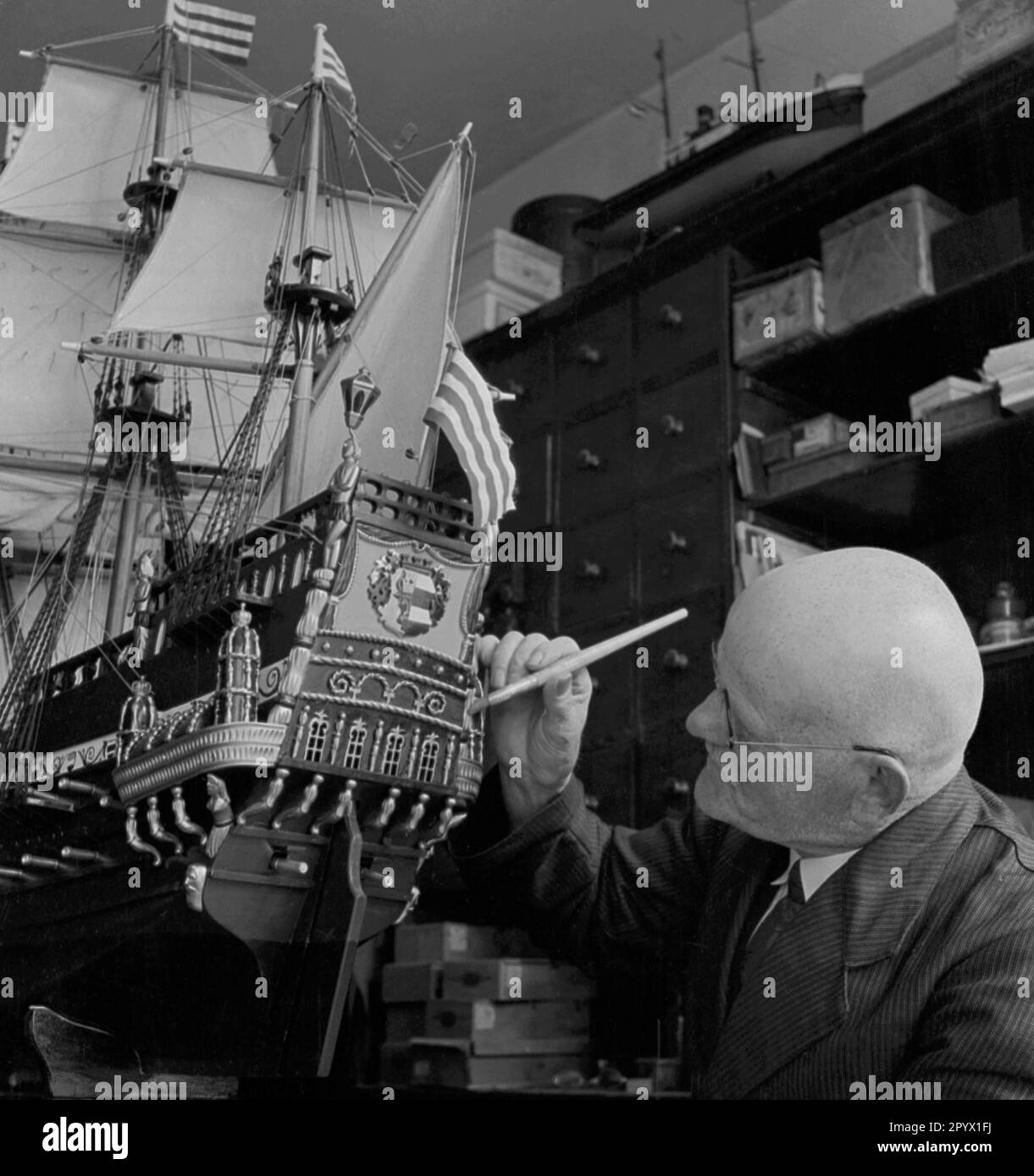The model maker Robert Daehncke working on one of his ship models. Stock Photo