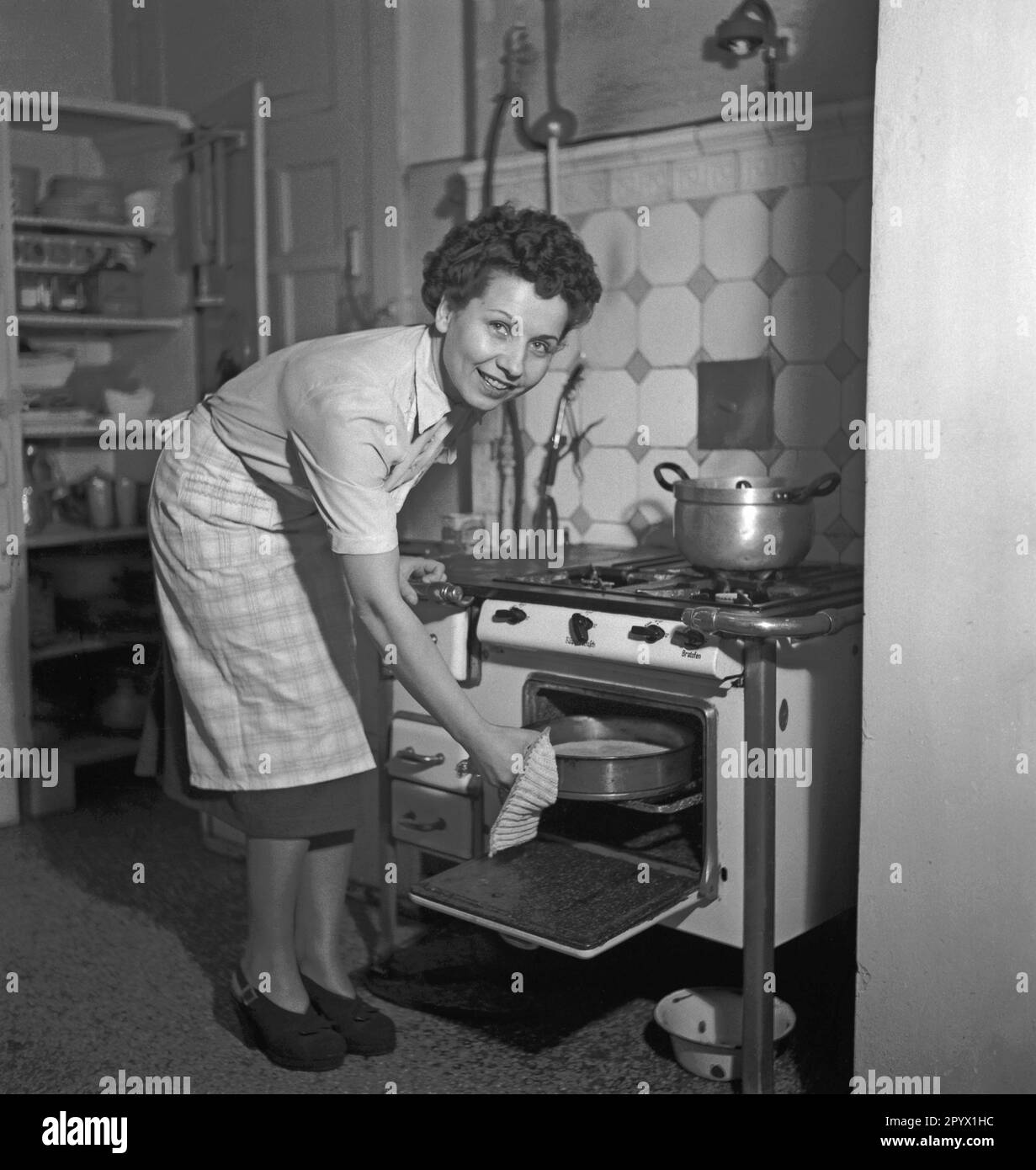 'Housewife while working at the stove. Scene from the series ''We work together''. The photographer accompanies couples in their respective occupations.' Stock Photo