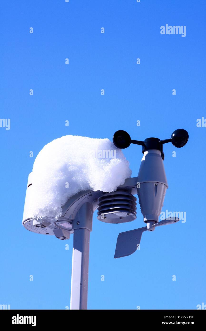 Home weather station outdoor sensors covered in snow against a blue winters sky Stock Photo