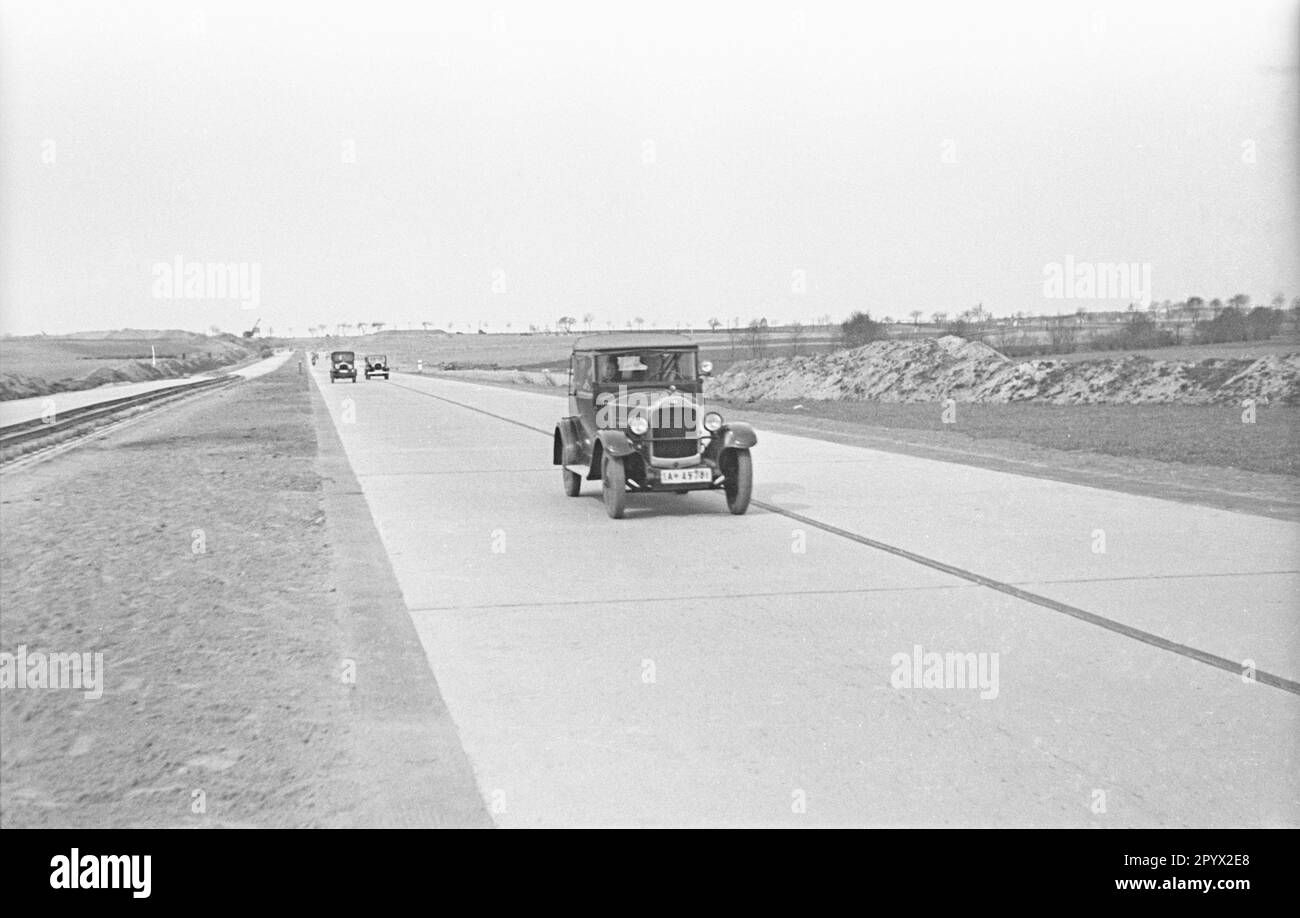 The first cars drive over the new highway. Here probably a BMW Dixi from the year 1932. Stock Photo
