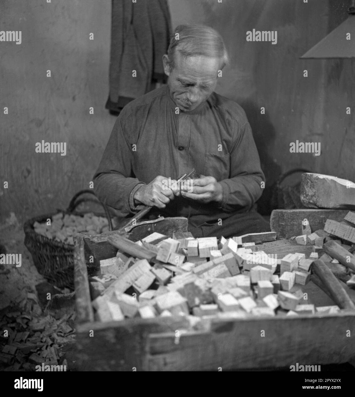 An older man brings the previously made smaller pieces of cork into the desired shape. Undated photo, probably in the 1930s. [automated translation] Stock Photo