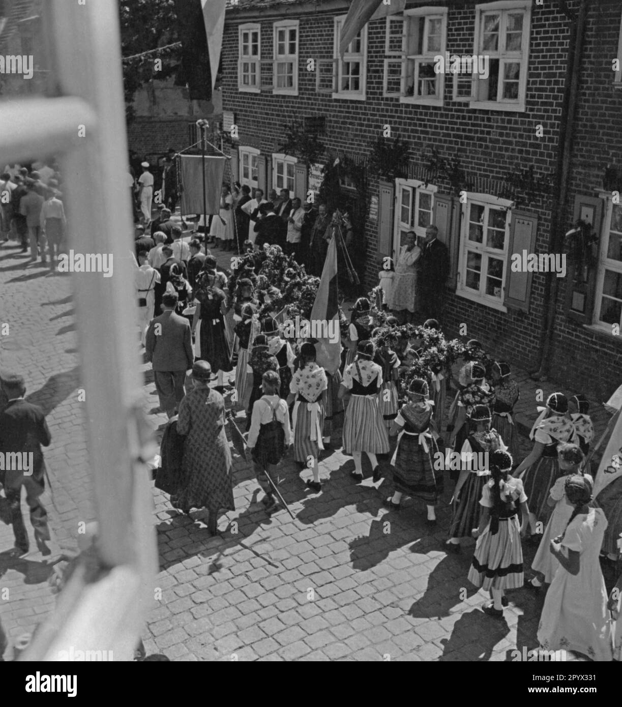 On the occasion of the children's festival in Plau a parade was organized through the streets of Plau. In this picture are mostly small girls in traditional clothes, carrying flower wreaths and flags accompanied by several adults (undated shot). Stock Photo