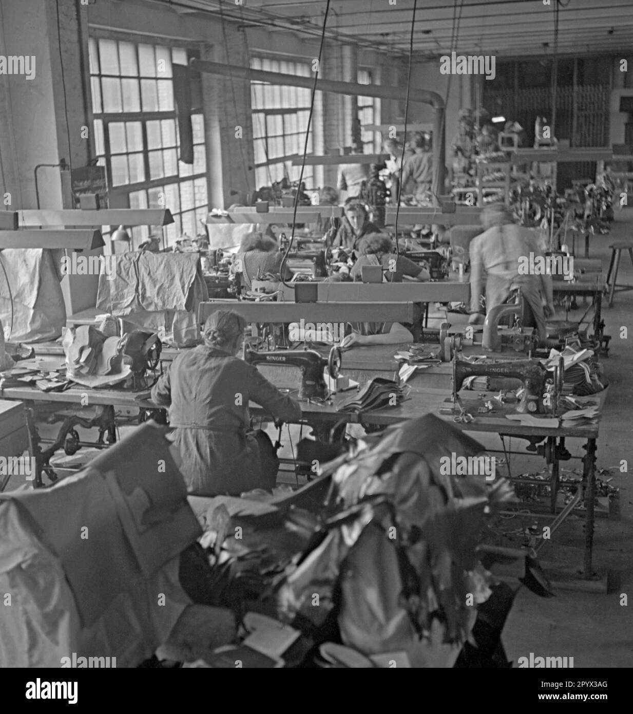 Women make children's shoes in a sewing room, for the Berlin Children's Fund of the United Nations. Undated photo. Stock Photo