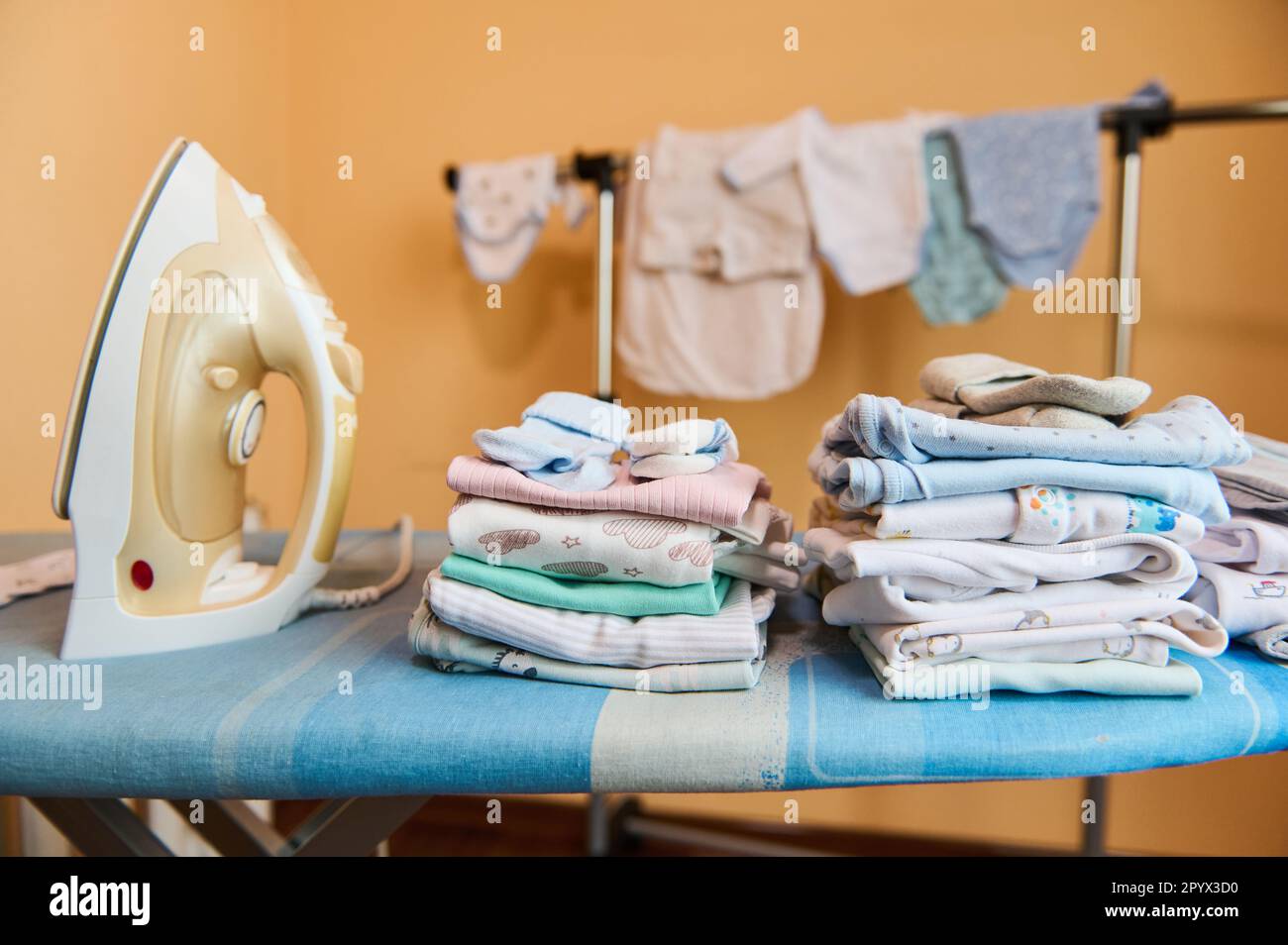 Clean laundered baby clothes ironed and folded in stack near steam