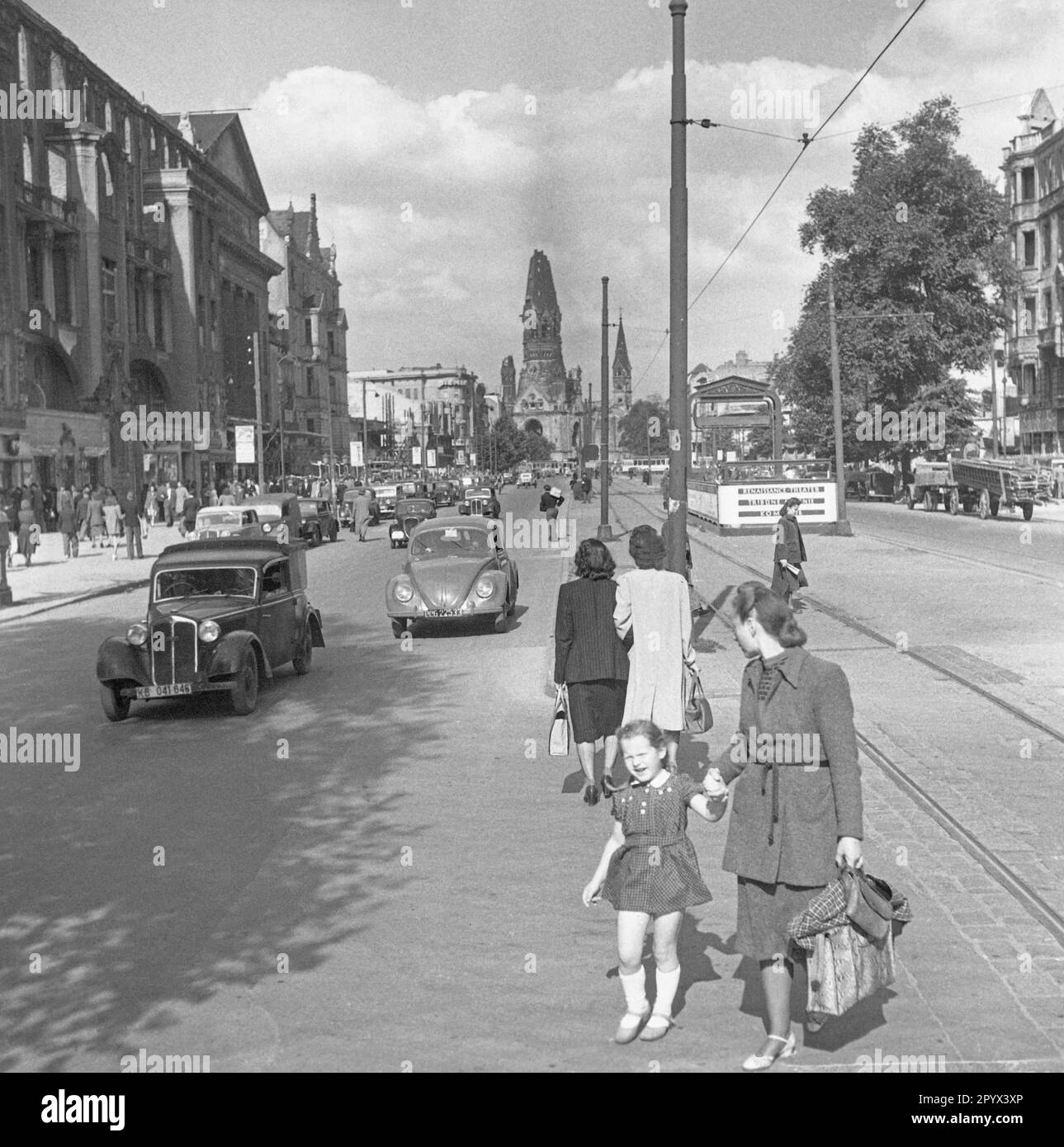 Undated photo of a street scene at the Kurfuerstendamm in West Berlin, British occupation zone, in the summer of 1950. In the foreground, pedestrians crossing the street. On the right, partially destroyed houses. In the background, the entrance to the underground station Kurfuerstendamm. Behind, the ruined tower of the Kaiser Wilhelm Memorial Church (Hollow Tooth). Stock Photo