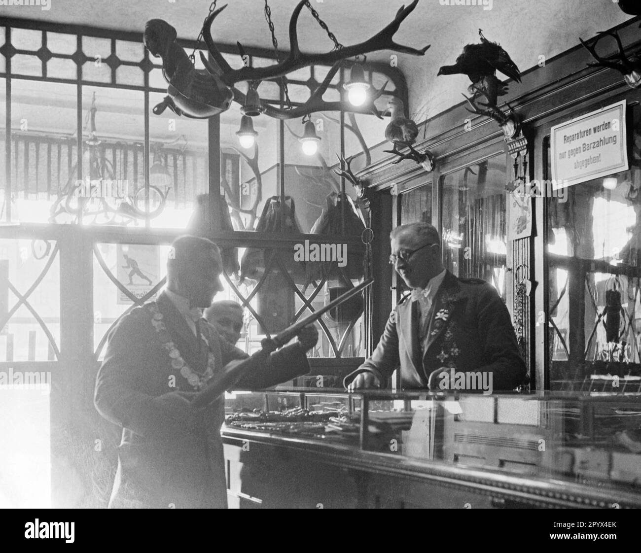 Members of a Rostock shooting club in a gun shop. Deer antlers and stuffed birds hang on the wall. Undated picture. Stock Photo
