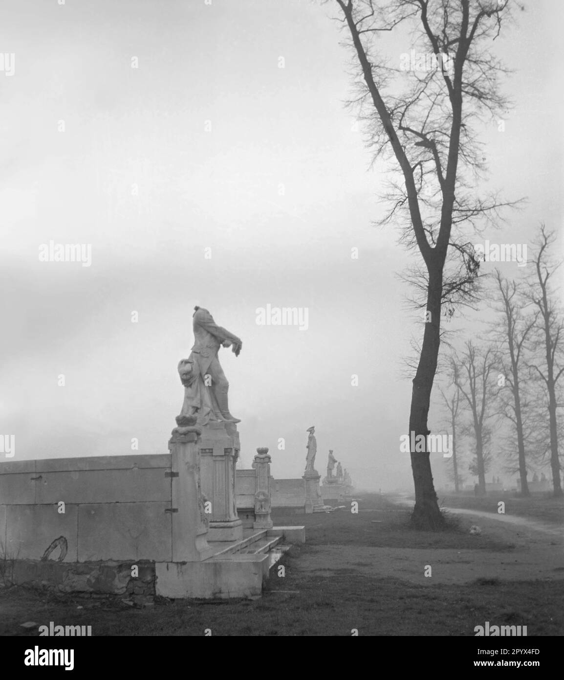 Undated photo of the Neo-Baroque marble statue of King Frederick William II of Prussia (the fat Luederjahn, 1744-1797, artist Adolf Bruett), which was partially destroyed by the shelling and vandalism of Soviet soldiers (missing head), in the Grosse Sternallee in the Tiergarten in Berlin. The statue is presented with a view (northwest ) of the shimmering statue of King Frederick William III. (1770-1840, sculptor Gustav Eberlein) in the fog and the Victory Column at the Great Star in West Berlin, a former British occupation zone, 1950. Stock Photo