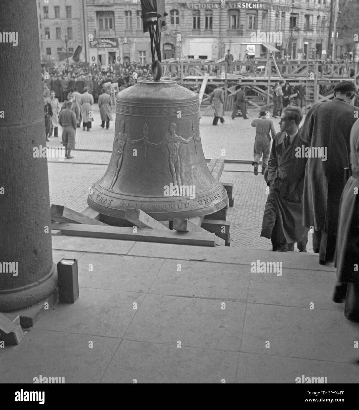 Photo of the Freedom Bell on Rathausplatz as it is being erected by a crane from a wooden frame shortly before its installation in the tower of the seat of the Governing Mayor of Berlin, Ernst Reuter (1948-1953) on October 21, 1950. On the left, one of the columns of the main doorway. In the background, soldiers of the U.S. Army, passers-by and journalists. The bell sounded for the first time at the ceremony on the United Nations Day (UN) on 24 October. Stock Photo